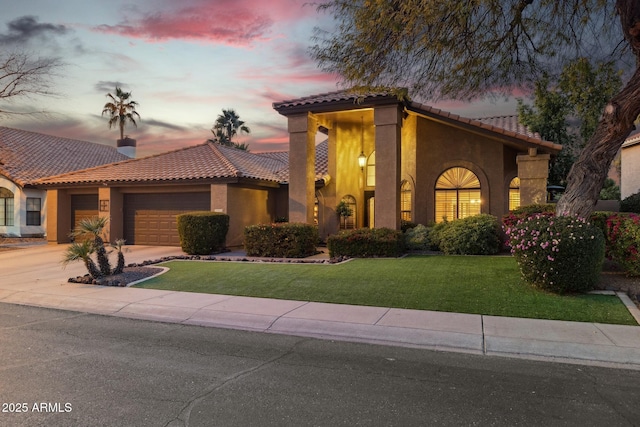 mediterranean / spanish house with a garage and a lawn