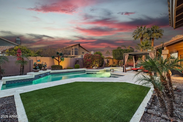 pool at dusk featuring a patio area and a lawn