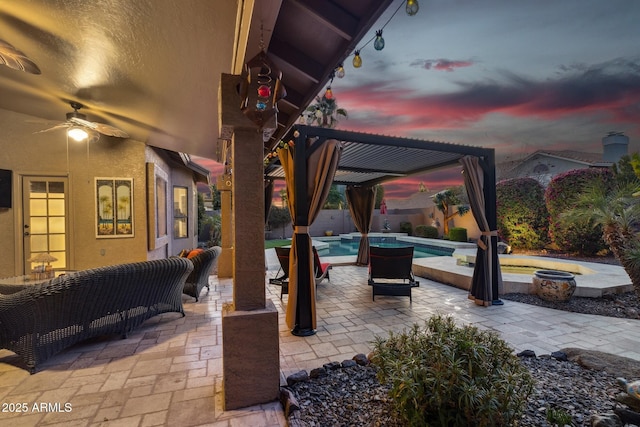 patio terrace at dusk with an outdoor living space with a fire pit, ceiling fan, and a pergola