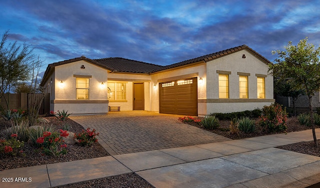 mediterranean / spanish home with a tile roof, decorative driveway, a garage, and stucco siding