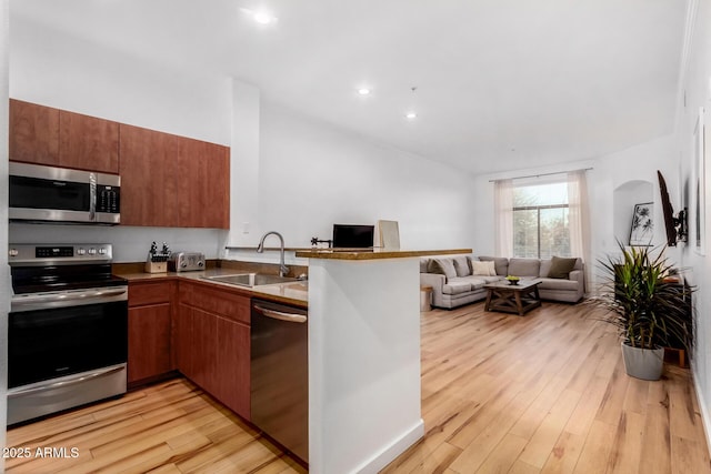 kitchen featuring stainless steel appliances, sink, light hardwood / wood-style flooring, and kitchen peninsula