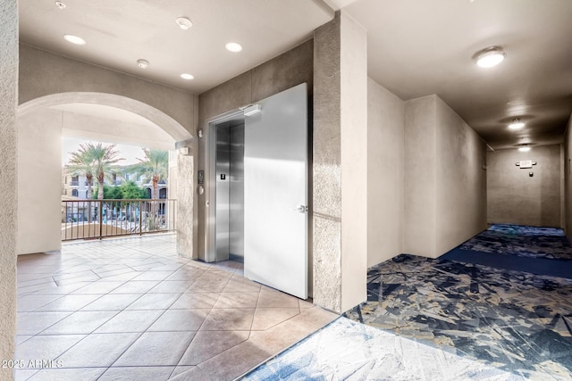 hallway featuring elevator and light tile patterned floors