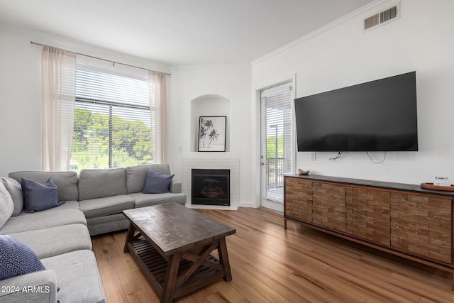 living room featuring ornamental molding, a brick fireplace, and hardwood / wood-style floors