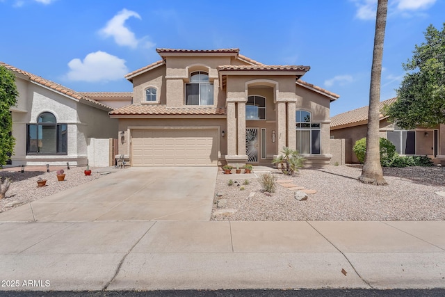 mediterranean / spanish home with stucco siding, a tiled roof, concrete driveway, and a garage