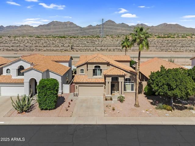 mediterranean / spanish home featuring driveway, a tiled roof, stucco siding, and a mountain view
