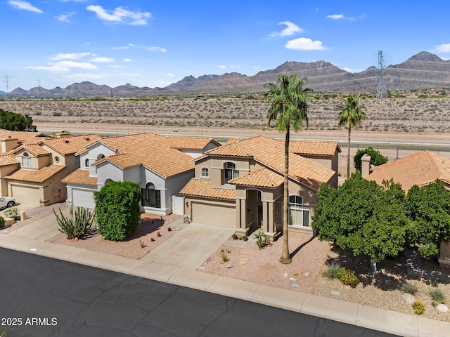 view of front of property featuring a mountain view, stucco siding, a tile roof, and concrete driveway