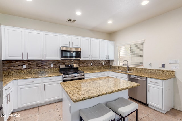 kitchen with stainless steel appliances, sink, light stone countertops, and white cabinets