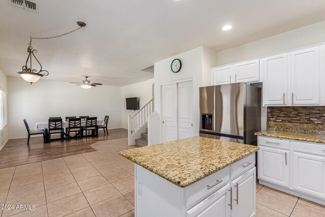 kitchen with hanging light fixtures, light wood-type flooring, stainless steel fridge, ceiling fan, and a kitchen island