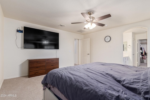 bedroom with ensuite bath, light carpet, a closet, a walk in closet, and ceiling fan