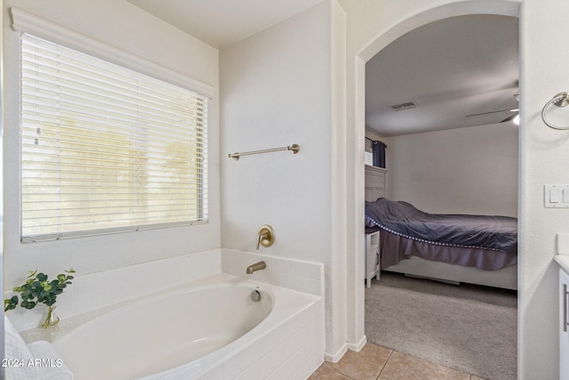 bathroom with tiled tub, vanity, plenty of natural light, and tile patterned floors