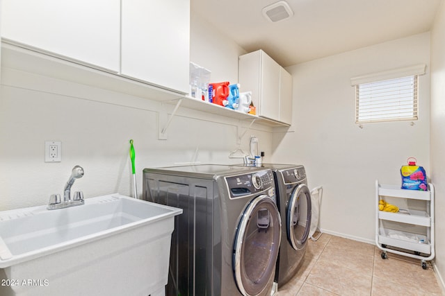 clothes washing area featuring washing machine and clothes dryer, cabinets, sink, and light tile patterned floors