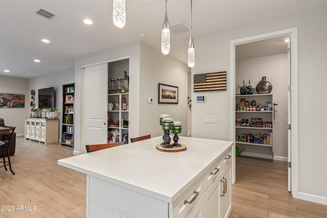 kitchen featuring a center island, pendant lighting, white cabinets, and light hardwood / wood-style flooring