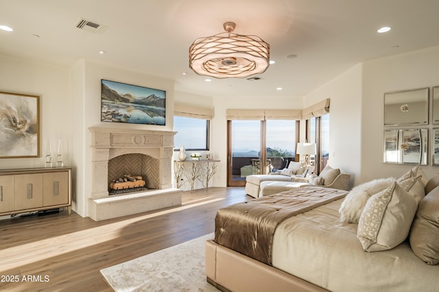 bedroom featuring recessed lighting, a fireplace, wood finished floors, visible vents, and access to outside