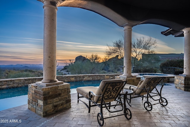 patio terrace at dusk with a pool with hot tub and a mountain view