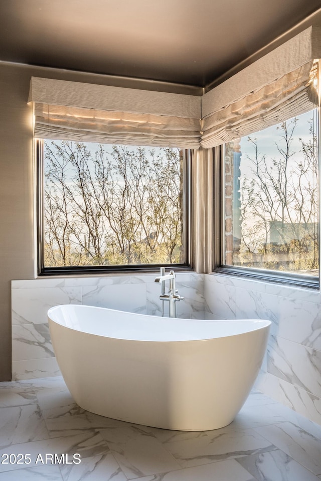 bathroom featuring a tub, plenty of natural light, and tile walls