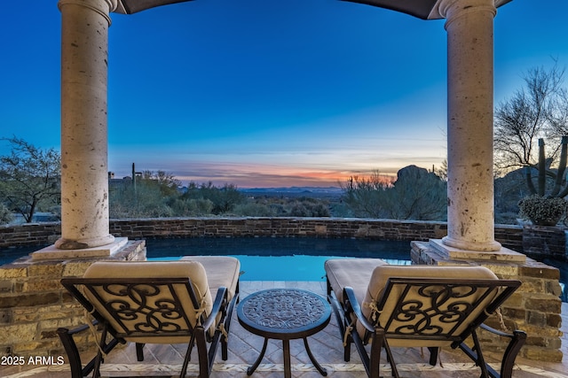 patio terrace at dusk featuring a balcony