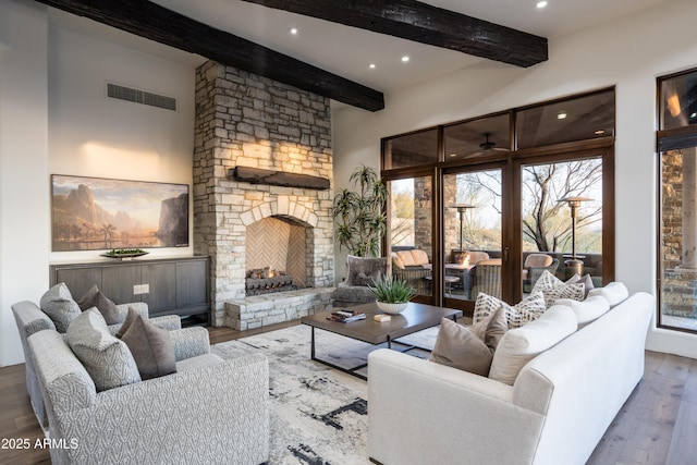 living area featuring recessed lighting, a fireplace, wood finished floors, visible vents, and beamed ceiling