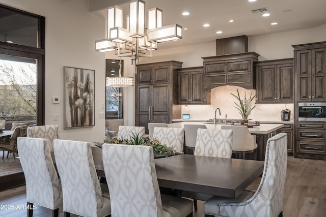 dining area featuring recessed lighting, visible vents, an inviting chandelier, and wood finished floors