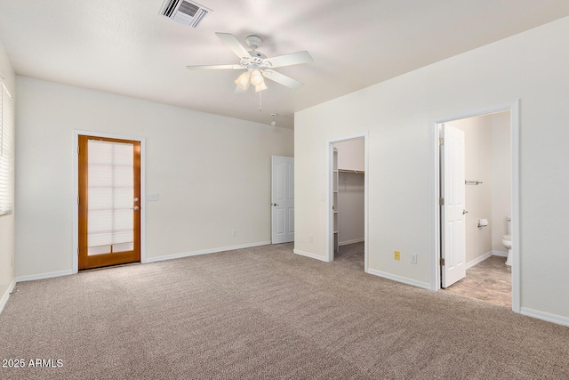 unfurnished bedroom with connected bathroom, a walk in closet, ceiling fan, light carpet, and a closet