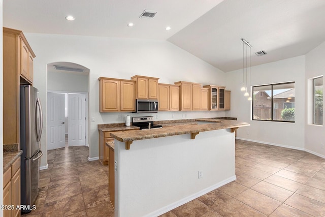 kitchen featuring stone countertops, appliances with stainless steel finishes, a kitchen island with sink, hanging light fixtures, and a kitchen bar