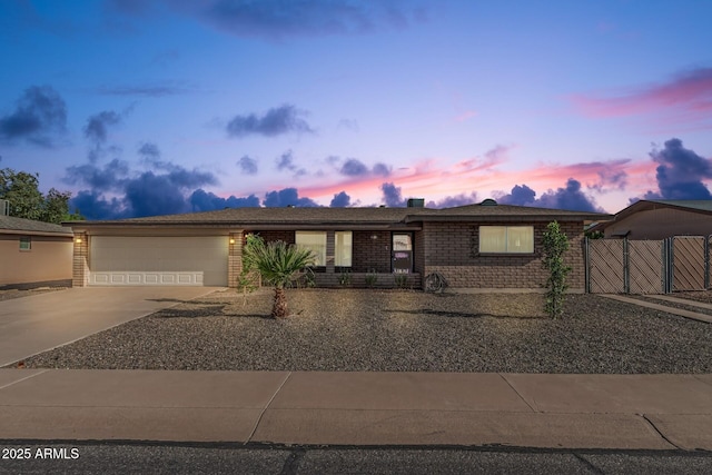 single story home with a gate, concrete driveway, a garage, and brick siding