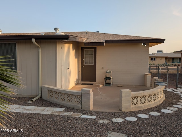 entrance to property featuring fence and a shingled roof