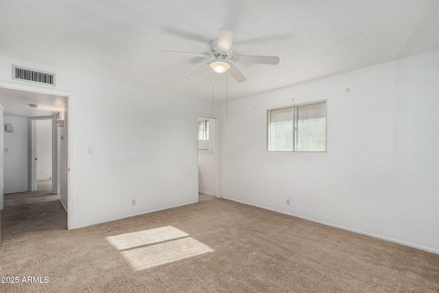 unfurnished room with visible vents, a ceiling fan, and carpet floors