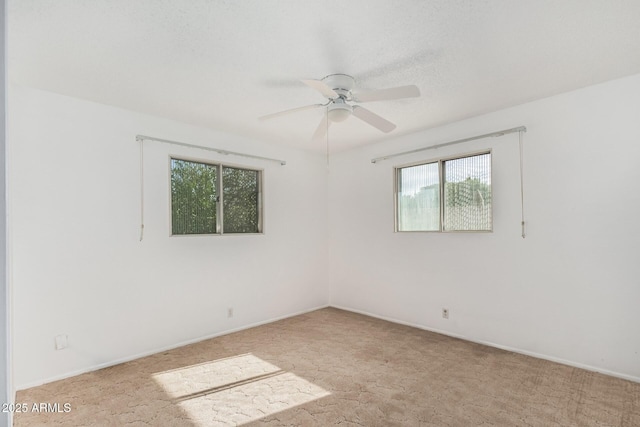 spare room featuring baseboards, a ceiling fan, carpet flooring, and a healthy amount of sunlight