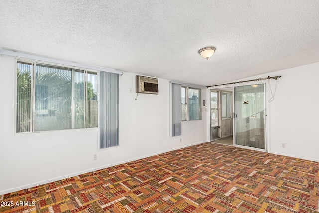 empty room featuring a textured ceiling, a wall mounted air conditioner, baseboards, and carpet floors