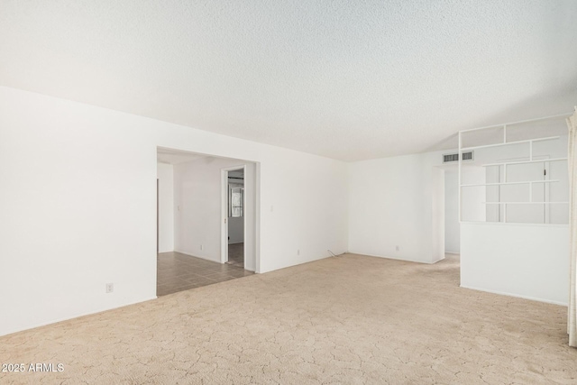 carpeted spare room with visible vents and a textured ceiling