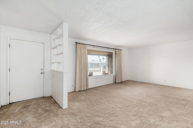 carpeted empty room featuring a textured ceiling