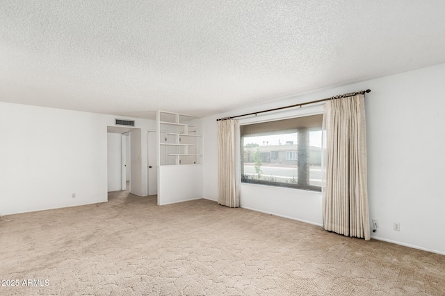 empty room featuring visible vents, carpet flooring, and a textured ceiling