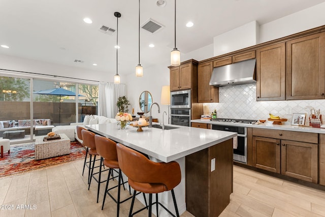 23083 N 74th Pl, Scottsdale, AZ 85255 - kitchen with ventilation hood, appliances with stainless steel finishes, backsplash, open floor plan, and a breakfast bar area