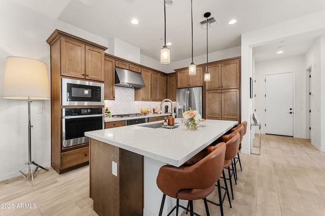 23083 N 74th Pl, Scottsdale, AZ 85255 - kitchen with stainless steel appliances, extractor fan, backsplash, brown cabinetry, and decorative light fixtures