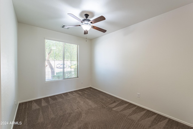 spare room featuring dark colored carpet and ceiling fan