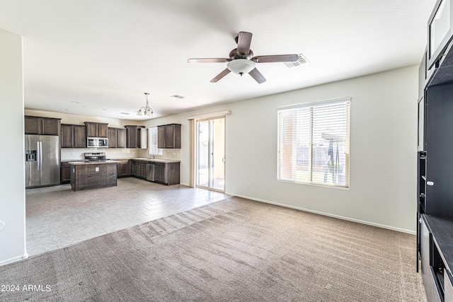 unfurnished living room with sink, light carpet, and ceiling fan with notable chandelier