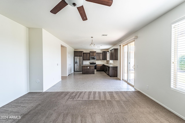 unfurnished living room with light colored carpet, ceiling fan, and sink