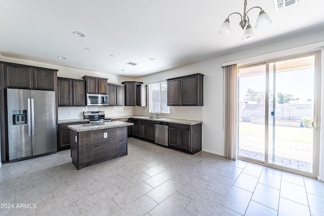 kitchen with stainless steel appliances, plenty of natural light, pendant lighting, and a center island