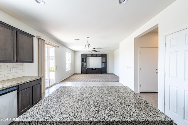 interior space featuring dishwasher, a kitchen island, light stone counters, and ceiling fan