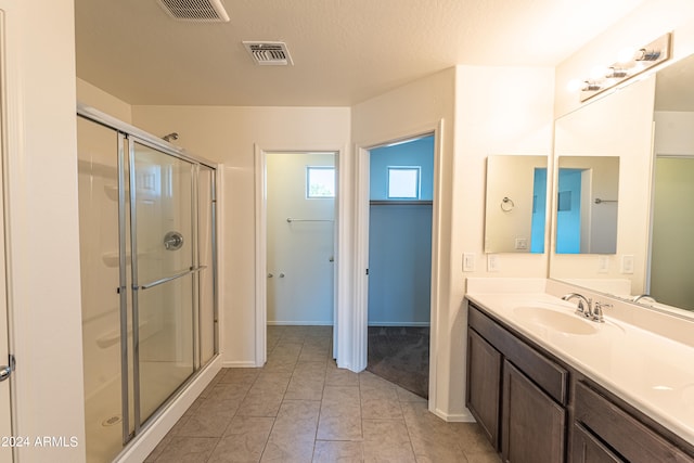 bathroom featuring vanity, walk in shower, tile patterned flooring, and a textured ceiling