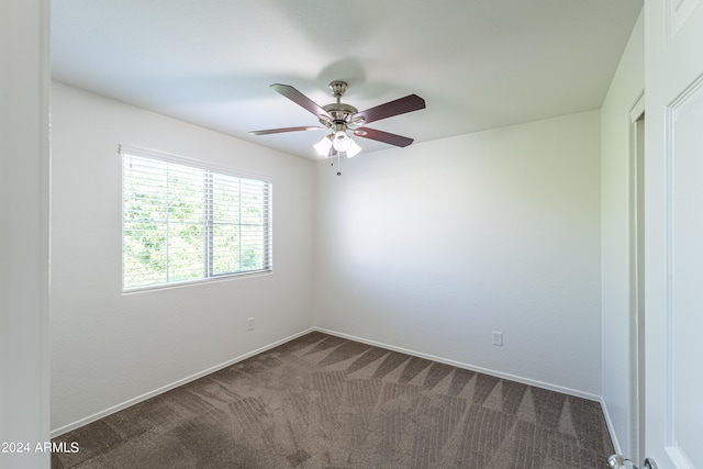 empty room with ceiling fan and dark colored carpet