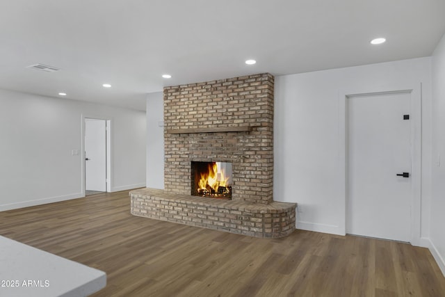 unfurnished living room featuring a brick fireplace and hardwood / wood-style floors