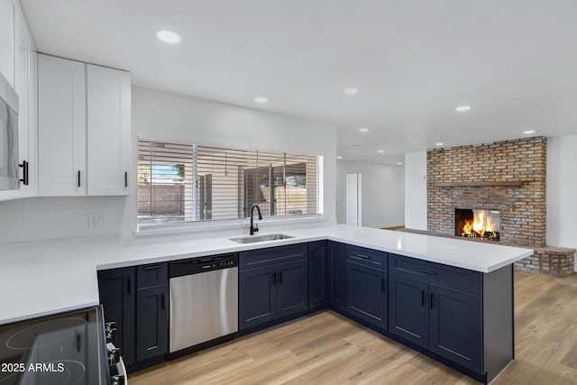 kitchen featuring stainless steel dishwasher, white cabinets, kitchen peninsula, and sink