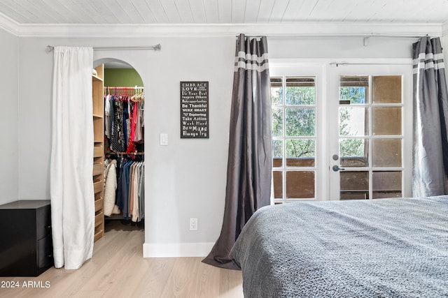 bedroom featuring a closet, a spacious closet, wooden ceiling, light wood-type flooring, and crown molding