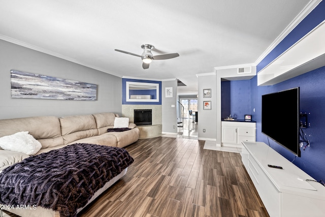 living room with a fireplace, dark hardwood / wood-style floors, crown molding, and ceiling fan