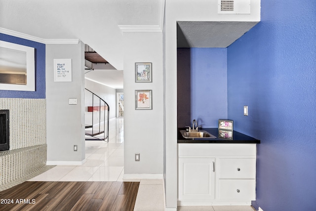 corridor with ornamental molding, light hardwood / wood-style flooring, a textured ceiling, and sink