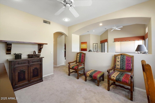 sitting room with ceiling fan, light colored carpet, and vaulted ceiling