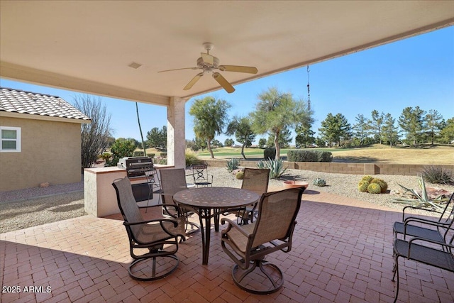 view of patio / terrace featuring grilling area, ceiling fan, and an outdoor kitchen