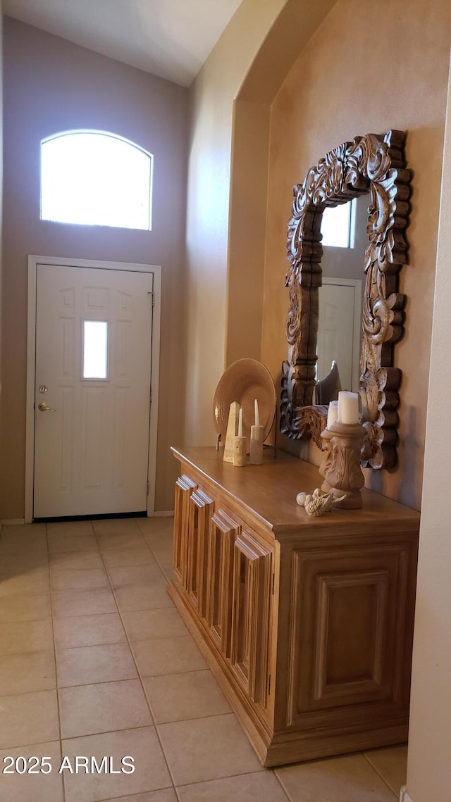 foyer featuring a healthy amount of sunlight, light tile patterned floors, and a towering ceiling