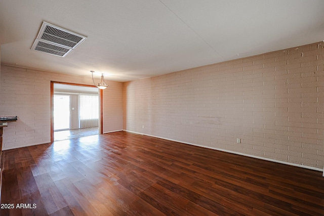 empty room featuring dark hardwood / wood-style floors and brick wall